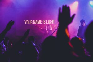 Concert with the words, "Your name will be light" in the background